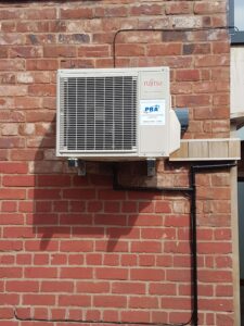 A Fujitsu outdoor wall mounted unit against red bricks installed by PRA Air Conditioning