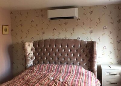 White air conditioning unit installed above a bed by PRA Air Conditioning Engineers