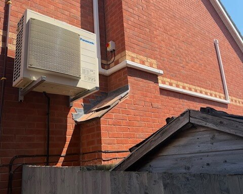 cropped AC outlet supported on outside of building